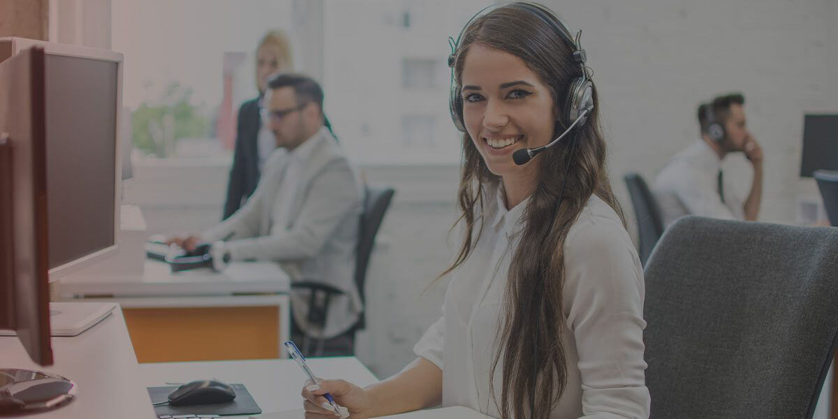 Portrait eines schönen und fröhlichen jungen Telefonvertreters mit Kopfhörer im Büro